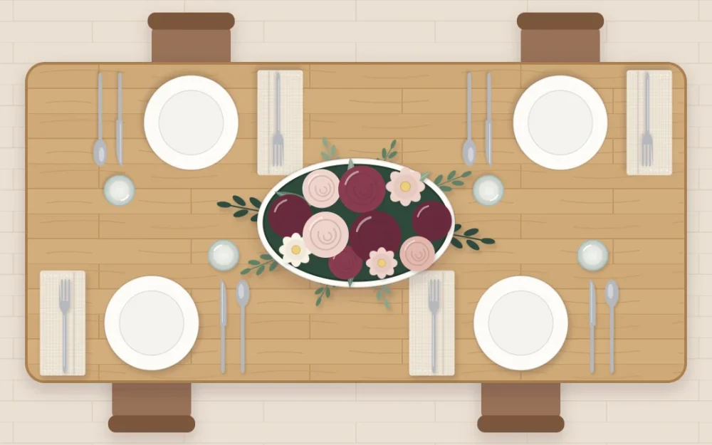 Top-down view of a rectangular table with one generous low arrangement of wine and blush flowers, plain ivory plates and pale napkins